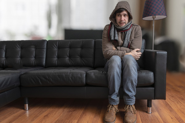 man on couch with broken heating system