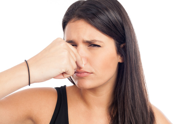 woman plugging nose from bad furnace odors