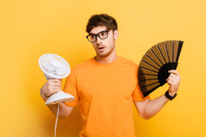 man cooling herself with a fan