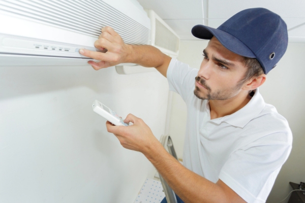 HVAC technician installing ductless air conditioner for a client