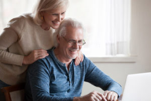 happy couple using laptop to search for air conditioner replacement company