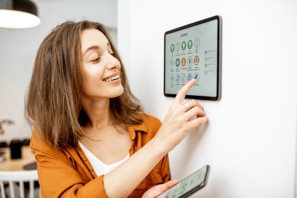woman controlling smart home thermostat and synching on her smart phone