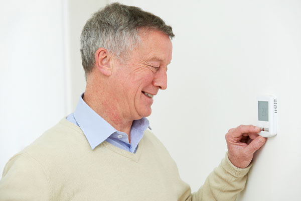 image of a homeowner adjusting a programmable thermostat