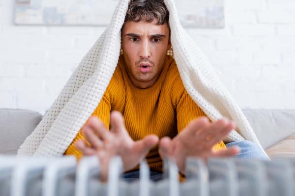 image of a homeowner in front of radiator depicting running out of heating oil