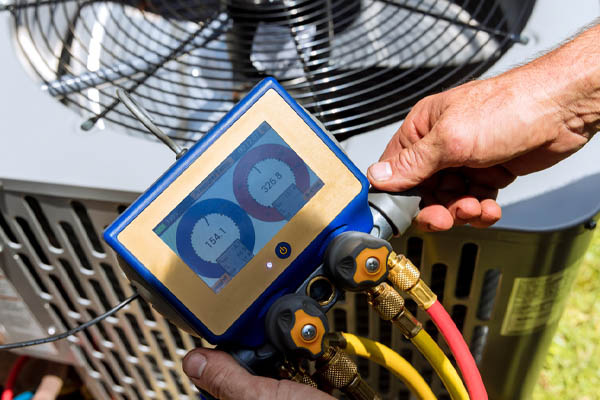 image of hvac contractor performing refrigerant refill on air conditioner