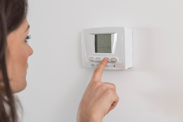 image of homeowner adjusting air conditioner thermostat fan settings