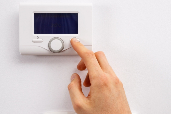 cropped view of a woman's hand turning on thermostat