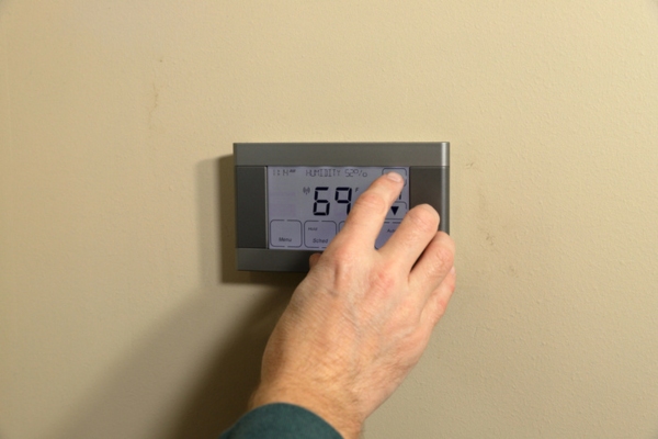homeowner adjusting HVAC thermostat