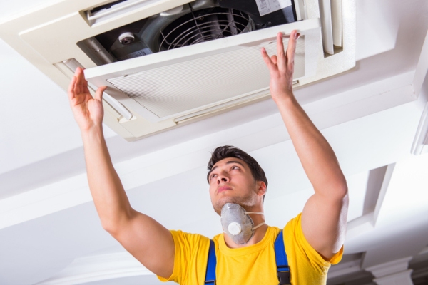 Repairman repairing ceiling air conditioning unit