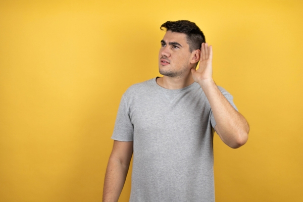 man looking up while cupping ear depicting Early Indicators of AC System Problems