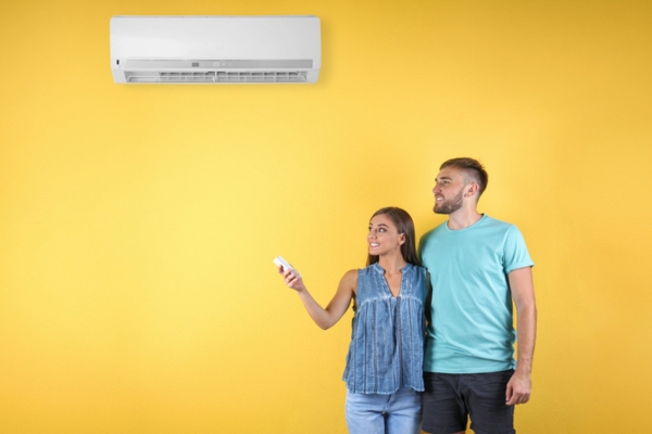 couple turning on new AC on yellow background
