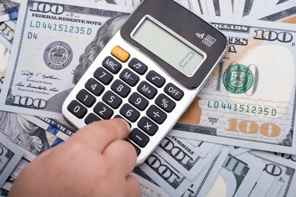 man pressing calculator on top of a stack of cash depicting Calculating Potential Energy Savings