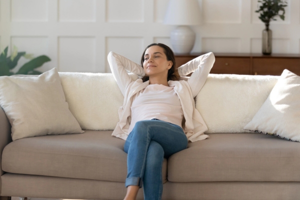 woman relaxing on the couch enjoying new AC benefits