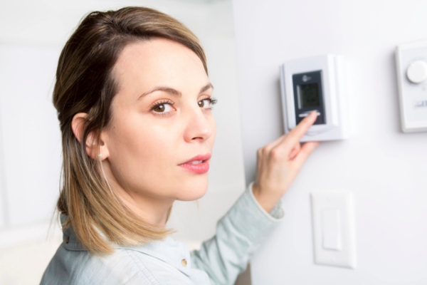 homeowner adjusting home indoor temperature using thermostat